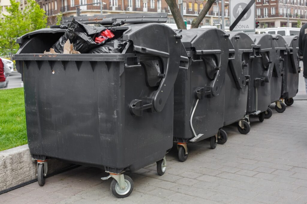 Large, black dumpsters lined up on the street